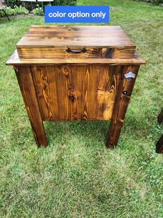 a wooden table sitting on top of a lush green field next to a blue sign that says color option only