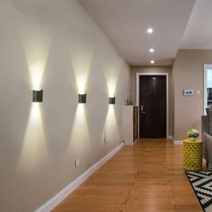 an empty room with three lights on the wall and a rug in front of it