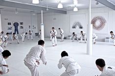 a group of men practicing karate moves in a room with white walls and flooring