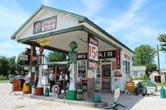 an old gas station with people standing around it