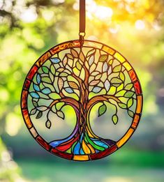 a stained glass tree ornament hanging from a string with the sun shining through it