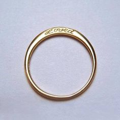 a gold wedding ring with the word love written on it's side, in front of a white background