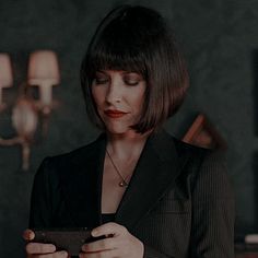 a woman looking at her cell phone while standing in a room with chandeliers