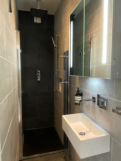 a bathroom with a walk in shower next to a white sink and mirror on the wall