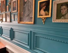 several paintings hang on the wall in an old - fashioned room with blue walls and white trim