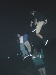 three skateboarders doing tricks in the dark