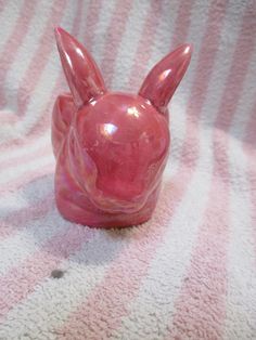 a pink glass rabbit figurine sitting on top of a blanket