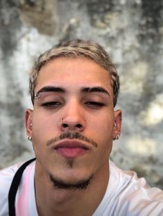 a man with piercings on his nose looking at the camera