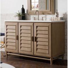 a bathroom vanity with shutter doors on the side and a mirror above it that has a plant next to it