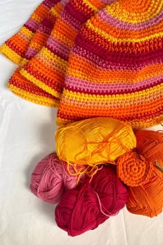 several balls of yarn sitting next to each other on a white tablecloth with crochet hooks