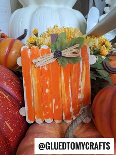 an orange pumpkin sitting on top of a table next to other pumpkins and flowers