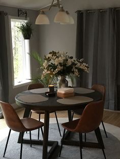 a dining room table with four chairs and a vase filled with flowers on top of it