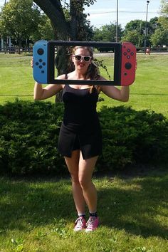 a woman holding up two nintendo wii game controllers in front of her face with both hands