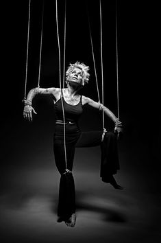 a woman hanging from strings with her hands and legs stretched out to the side, in black and white