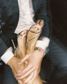 a man and woman sitting next to each other wearing high heeled shoes with clear straps