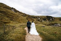 a bride and groom walking down a dirt path