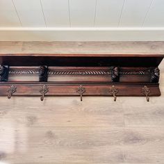 an old wooden shelf with four coat hooks on the top and two coats hanging from it's sides