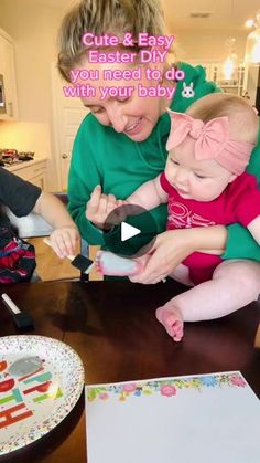 a woman holding a baby while sitting at a table