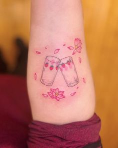 a woman's foot with pink flowers and two jars tattooed on the side of her leg