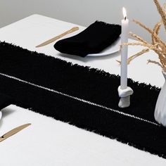 the table is set with black and white linens, silverware, and candles