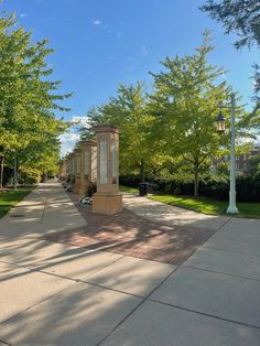 a clock tower sitting on the side of a road next to trees and grass covered ground