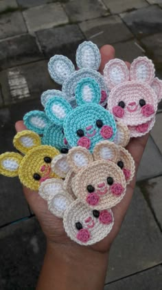 small crocheted animals are held in someone's hand on the sidewalk,