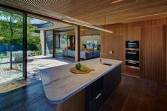 an open kitchen and living room area with wood flooring, large windows, and sliding glass doors