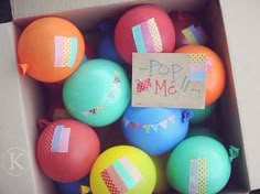 a box filled with lots of balloons and a sign that says pop me on it