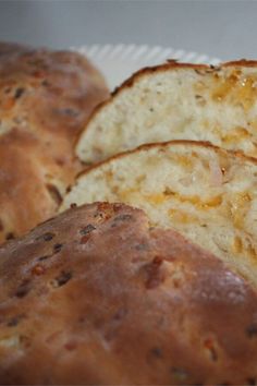 three loaves of bread sitting on top of a white paper plate next to each other