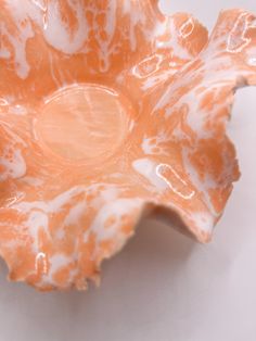 an orange and white flower shaped bowl sitting on top of a table