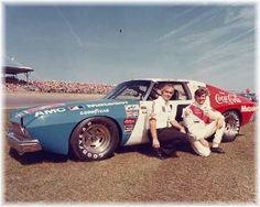 two men sitting on the back of a race car