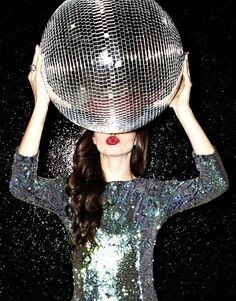 a woman holding a disco ball over her head