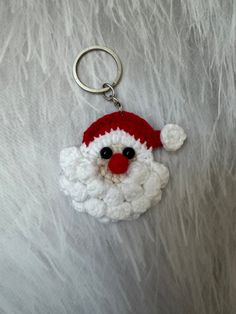 a white and red santa claus keychain with a black eye on it's face