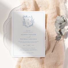 a white and blue wedding stationery on a plate with a flower in the middle