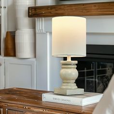 a white lamp sitting on top of a wooden table next to a fire place in a living room