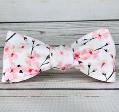 "Pale pink cherry blossoms on white cotton sateen. Because of the handmade nature of these bowties they can vary in size ever so slightly but on average the bow measures 5 inches by 2 inches when tied. hand wash/ spot wash only The self-tied option will be made in the style pictured. The pre-tied option will have the addition of a hook in the back, and the bow will be stitched in the tied position. RETURNS: I accept returns on items in original, unused condition. You will receive a refund for th Elegant Bow For Gift In Spring, Spring Wedding Bow, Elegant Bow Tie For Spring Gifts, Pink Bow Gift For Spring, Decorative Bow For Spring Gifts, Pink Butterfly Knot Bow For Summer, Elegant White Bow Tie For Spring, White Summer Bow For Gifts, Spring Butterfly Knot Bow Gift