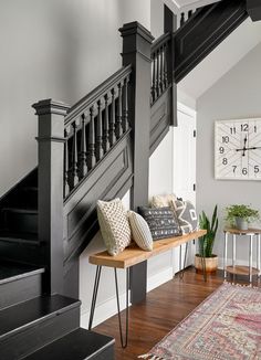 a wooden bench sitting under a staircase next to a clock