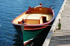 a small wooden boat tied to a dock next to the water with a bottle in it