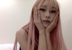 a woman with long pink hair is posing for the camera and holding her hands to her face