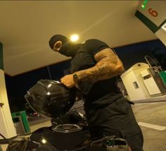 a man with tattoos on his arm is working on a motorcycle at a gas station