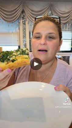 a woman is holding up a piece of pizza