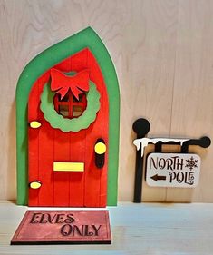 a red door with a wreath on it sitting next to a sign that says north pole elves only