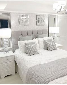 a bedroom with white bedding and silver accents