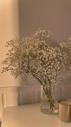 a vase with flowers on a table next to a candle