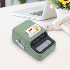 an electronic device sitting on top of a table next to a vase with yellow flowers