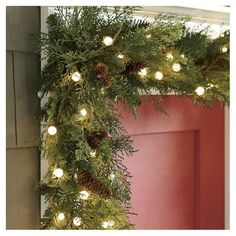 a wreath with pine cones and lights hanging from it's side on a door