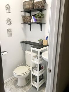 a white toilet sitting in a bathroom next to a shelf with baskets on top of it