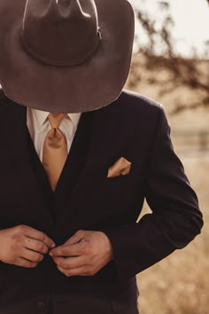 a man in a suit and tie with a cowboy hat on his head standing outside