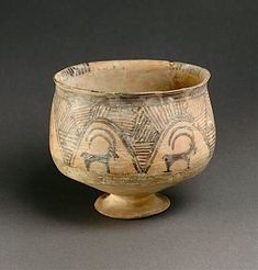 an old ceramic bowl with designs on the inside and outside, sitting on a gray surface