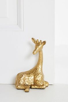 a gold giraffe figurine sitting in front of a white door,